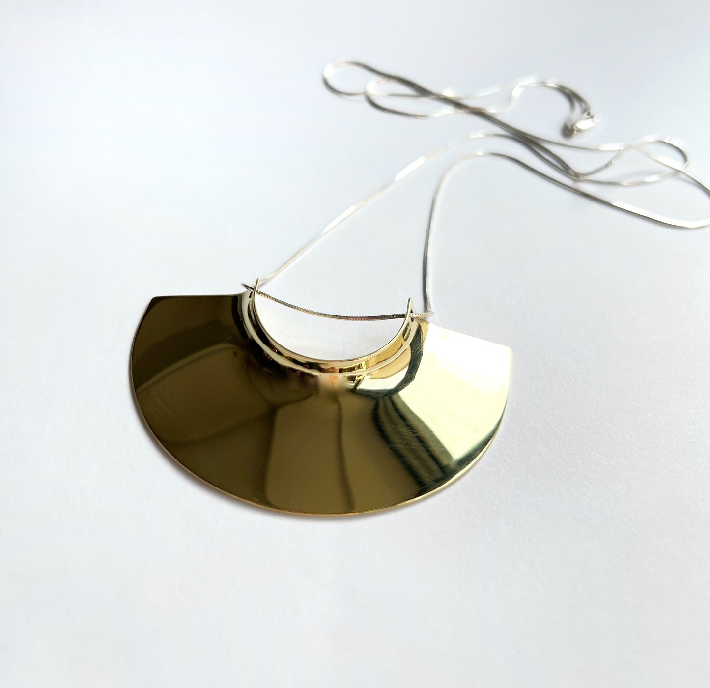 brass pendant laying flat facing towards you left on a white background