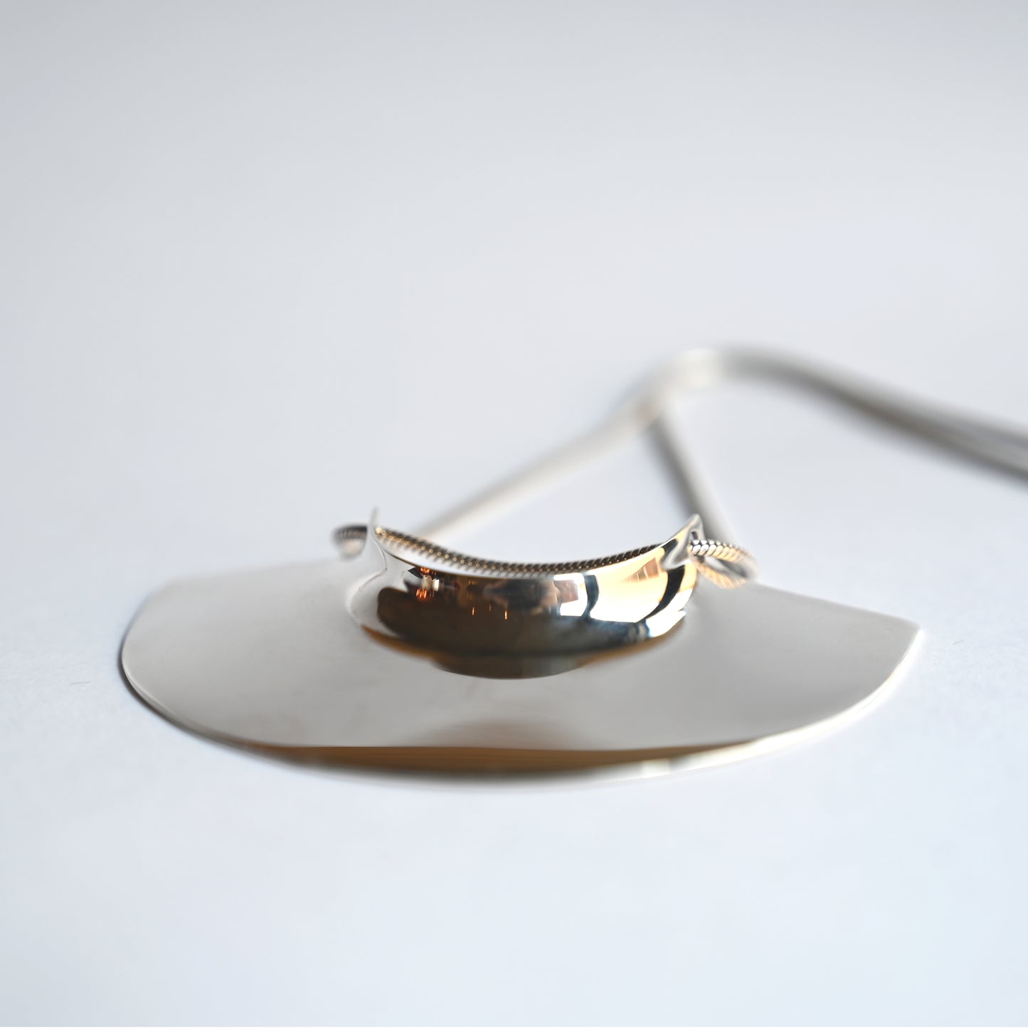 brass pendant laying flat facing forwards on a white background, close up