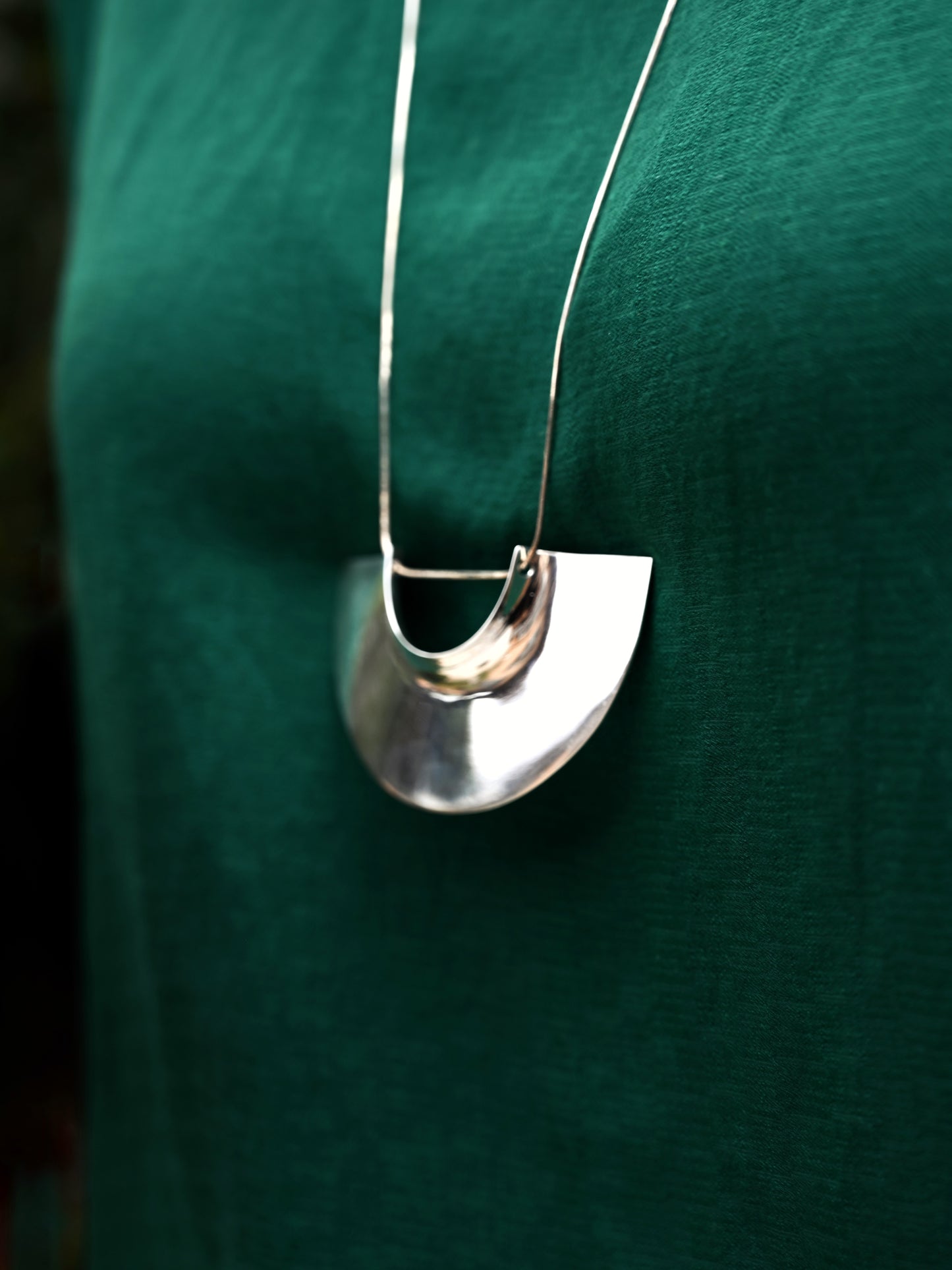 Detail view of assemblage pendant in silver with green blouse in background