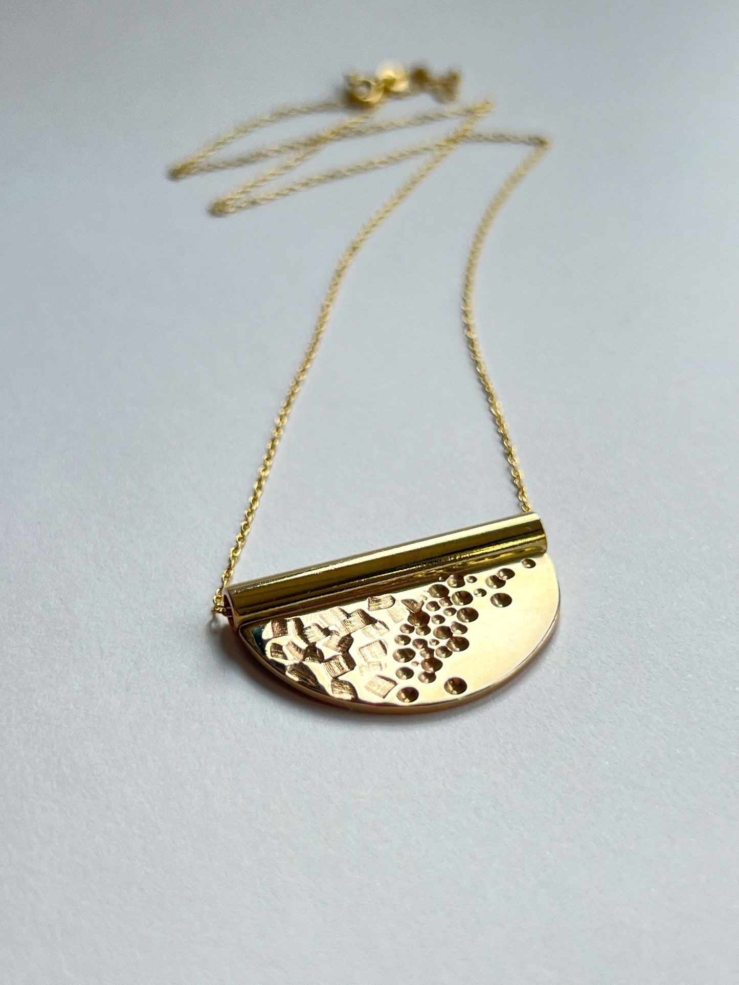 bronze tube necklace laying flat facing to the right with a white background