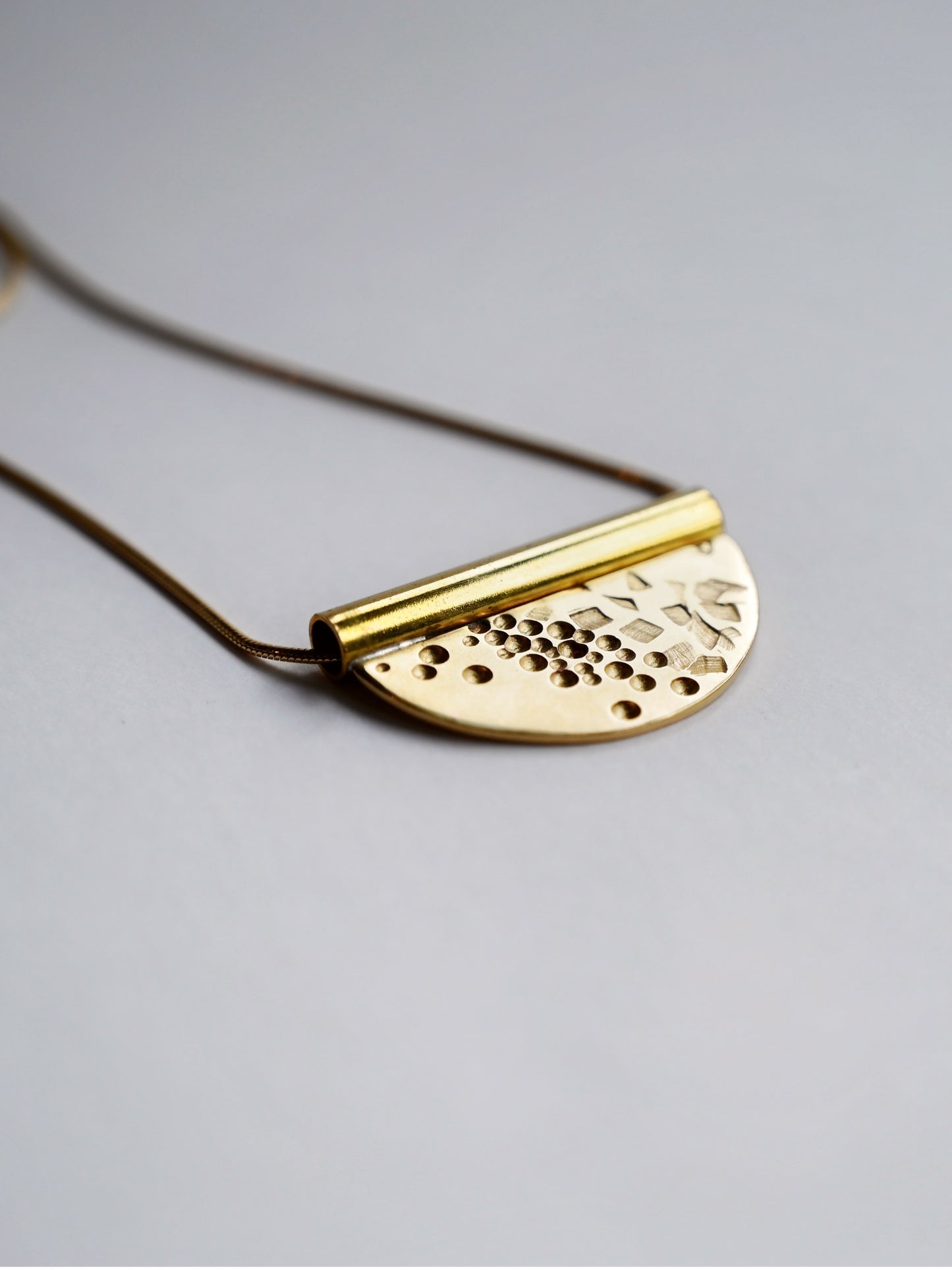 bronze tube necklace laying flat facing to the right close up with a white background