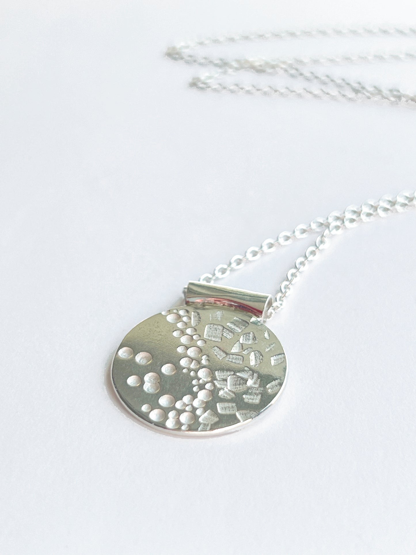 circle pendant laying flat close up facing to the left on a white background