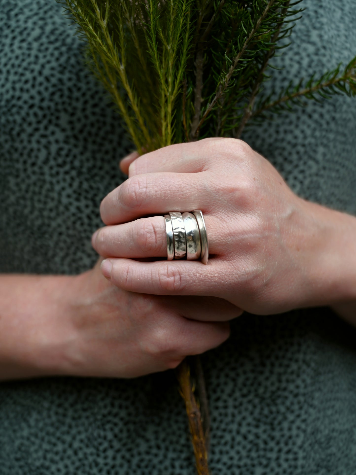 Element stacking set front view on ring finger with greenery and blue blouse with black dots in background