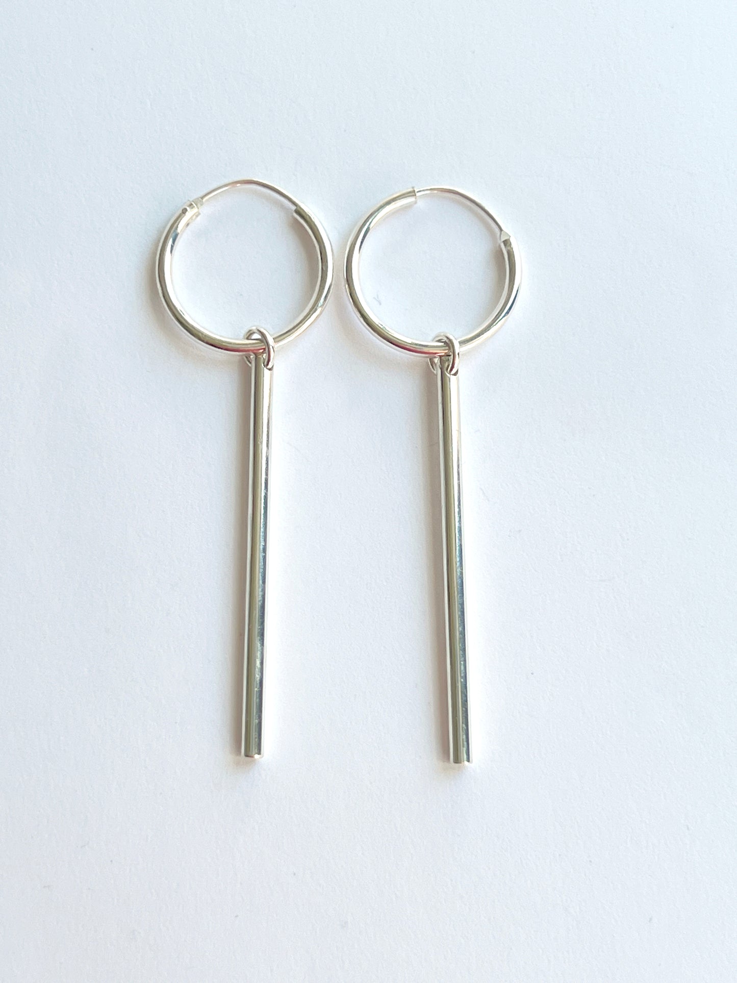 long tube dangle sterling silver hoops on a white background