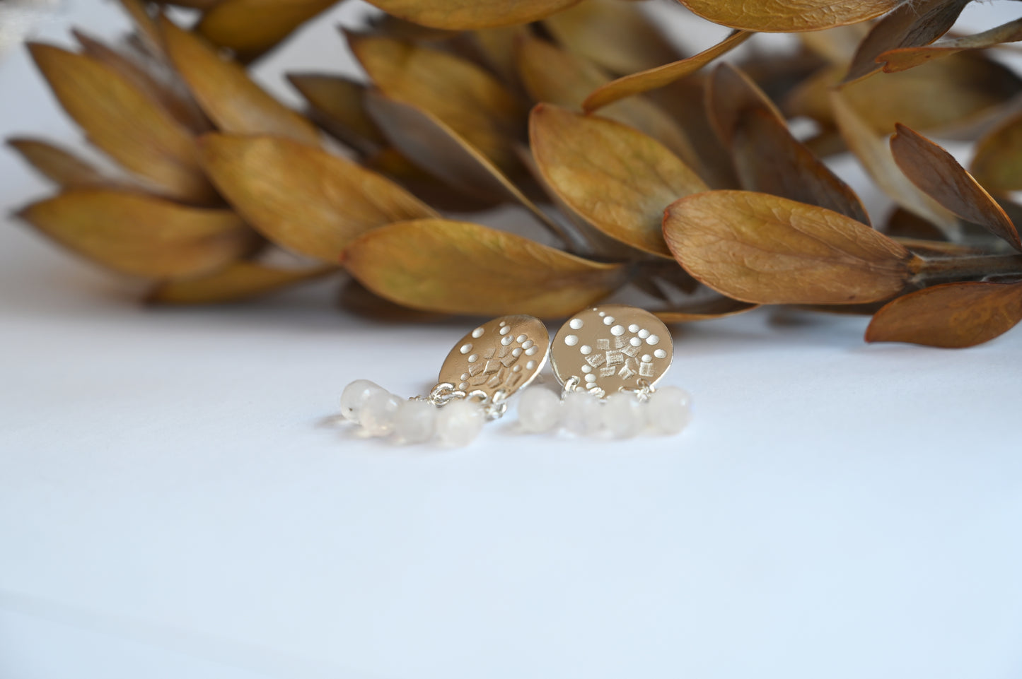 stud dangle earrings on a white ground with yellow leaves in the background