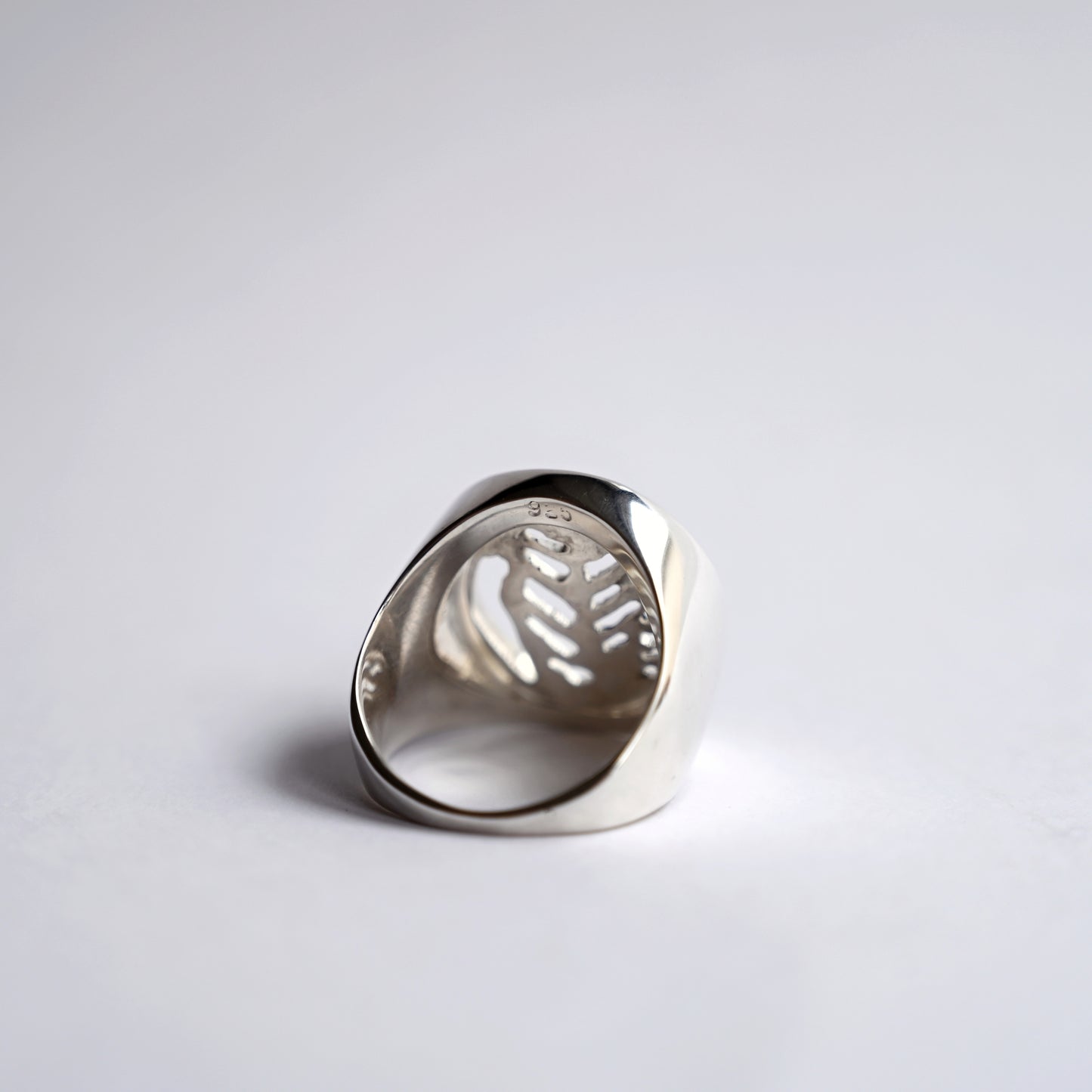 Back view of silver node ring with leaf cut out on white background