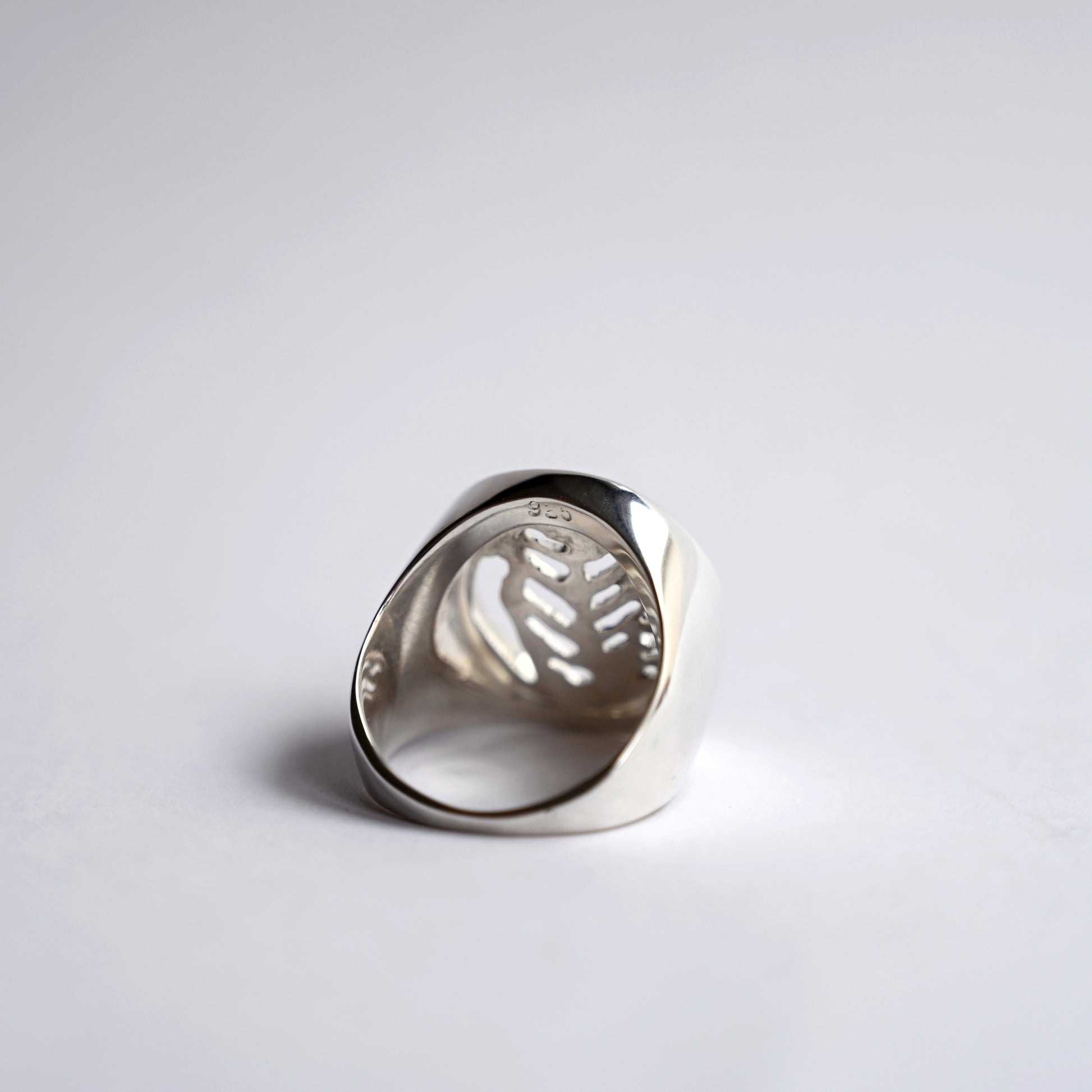 Back view of silver node ring with leaf cut out on white background