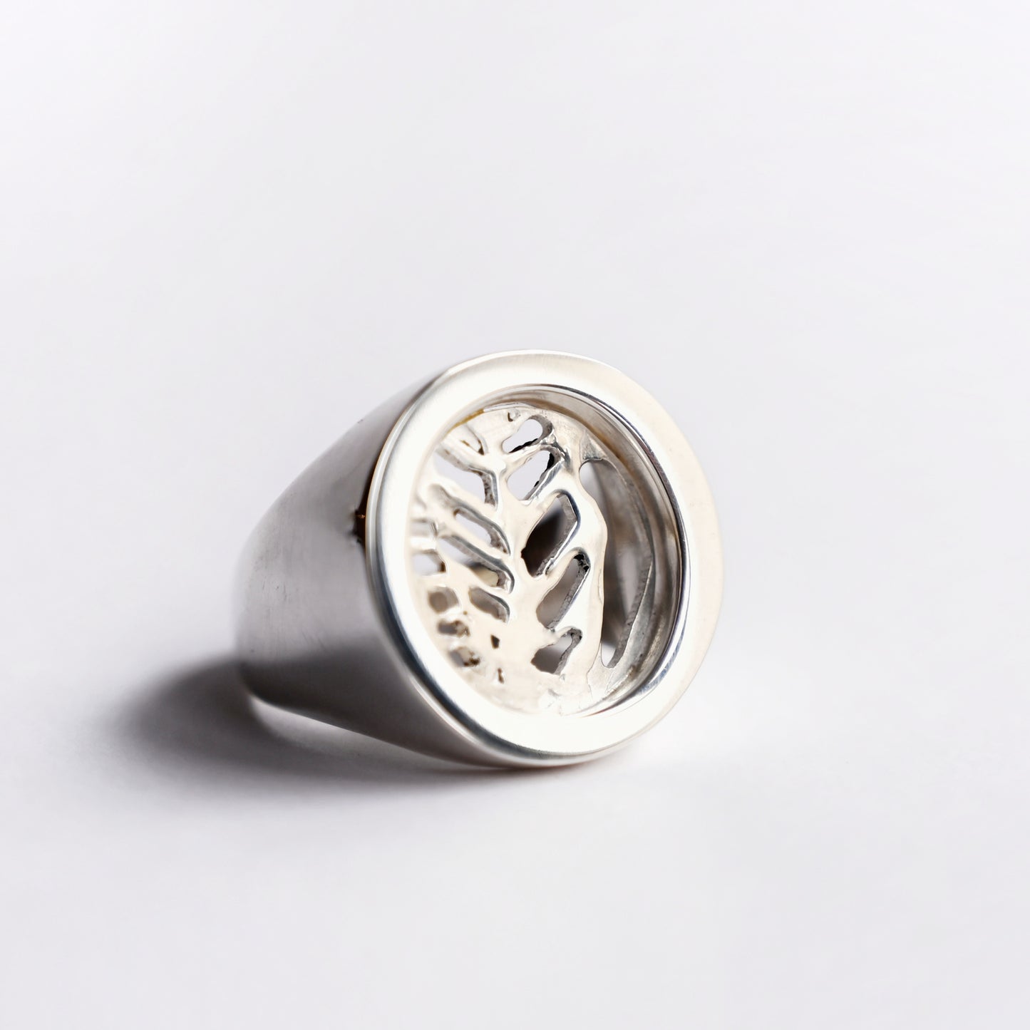 Front angled view of silver node ring with leaf cut out on white background