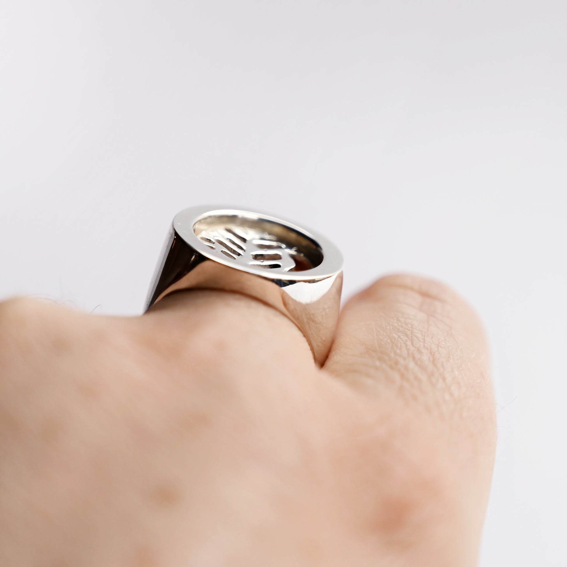 Side front view of silver node ring with leaf cut out on hand with white background
