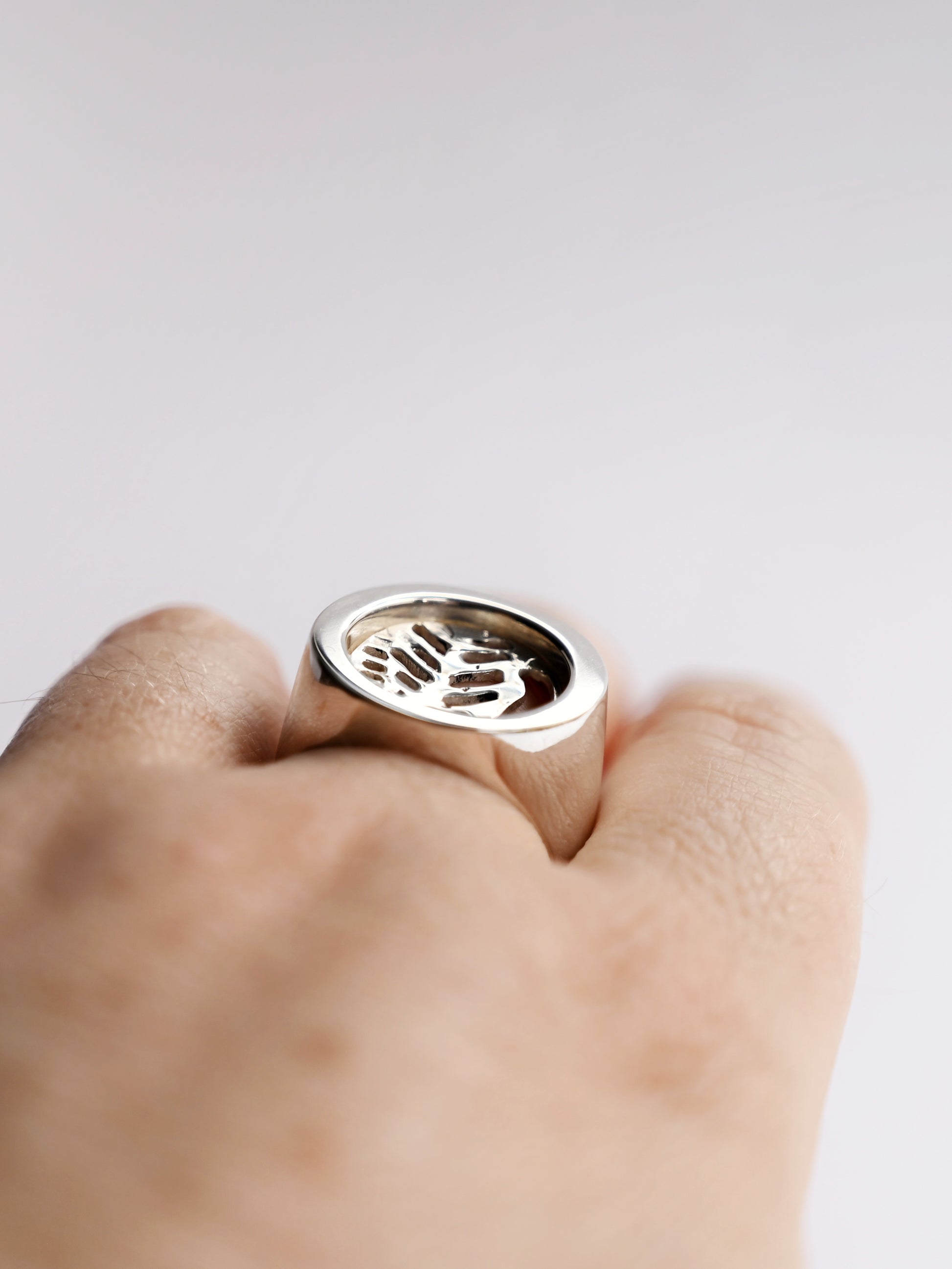 top side view of silver node ring with leaf cut out on hand with white background