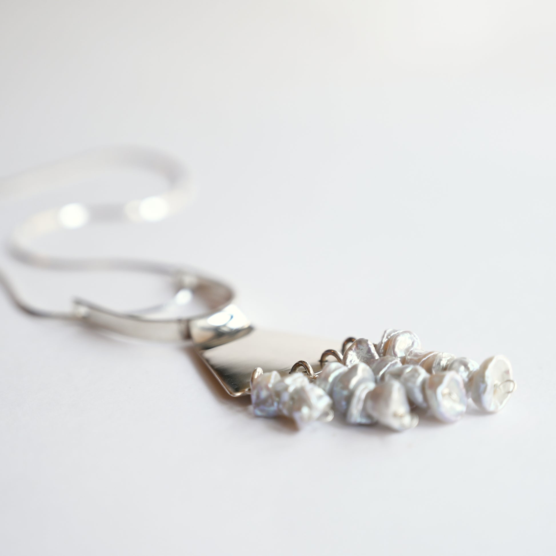 Art deco pendant in silver with pearls from side on white background