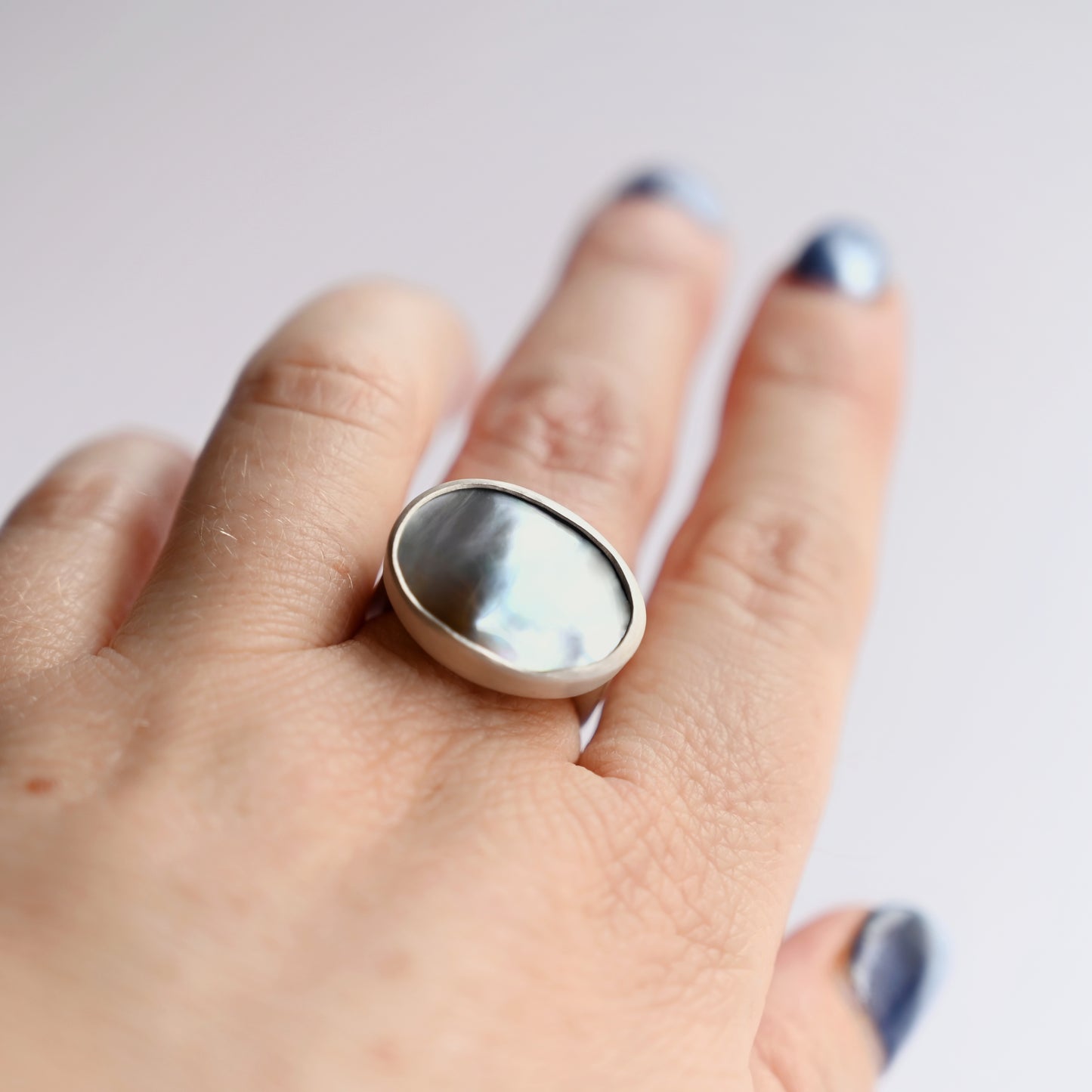 Top view of silver component ring with mabe pearl 1 on hand with white background