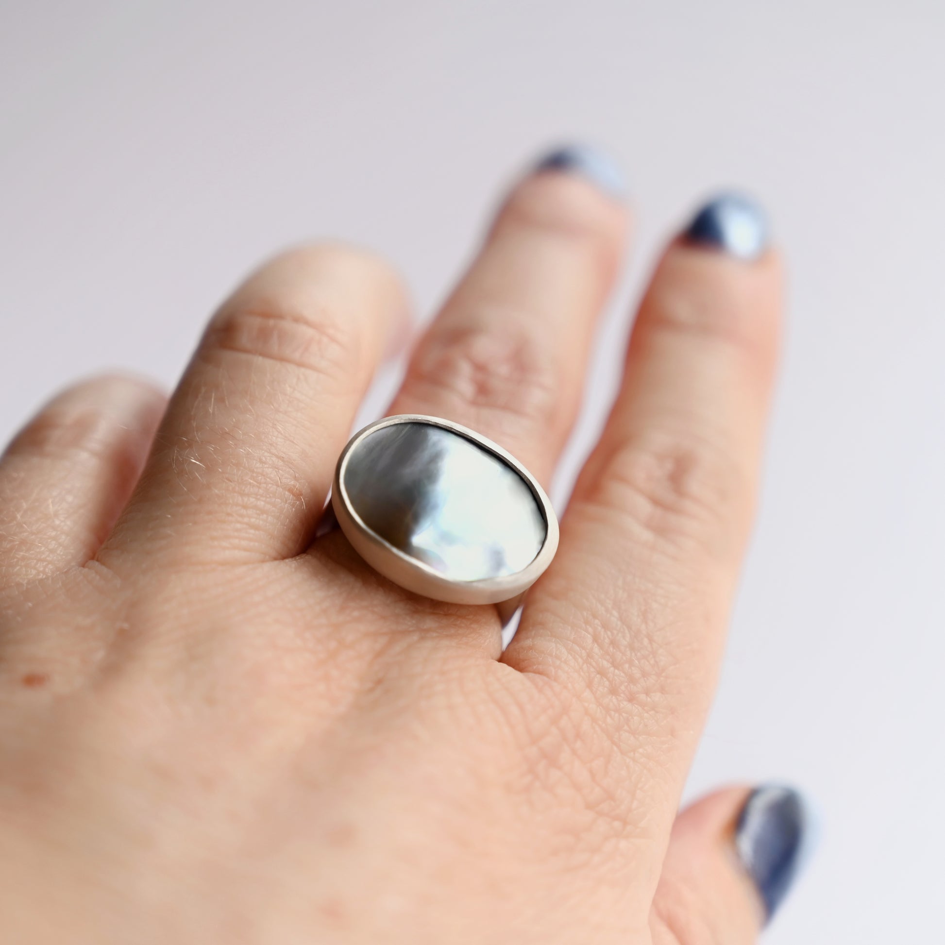 Top view of silver component ring with mabe pearl 1 on hand with white background