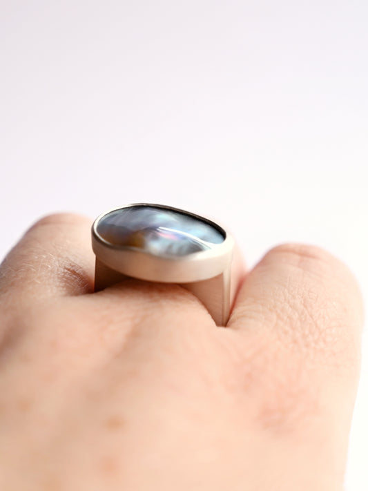 Close up view of silver component ring with mabe pearl 1 on hand with white background