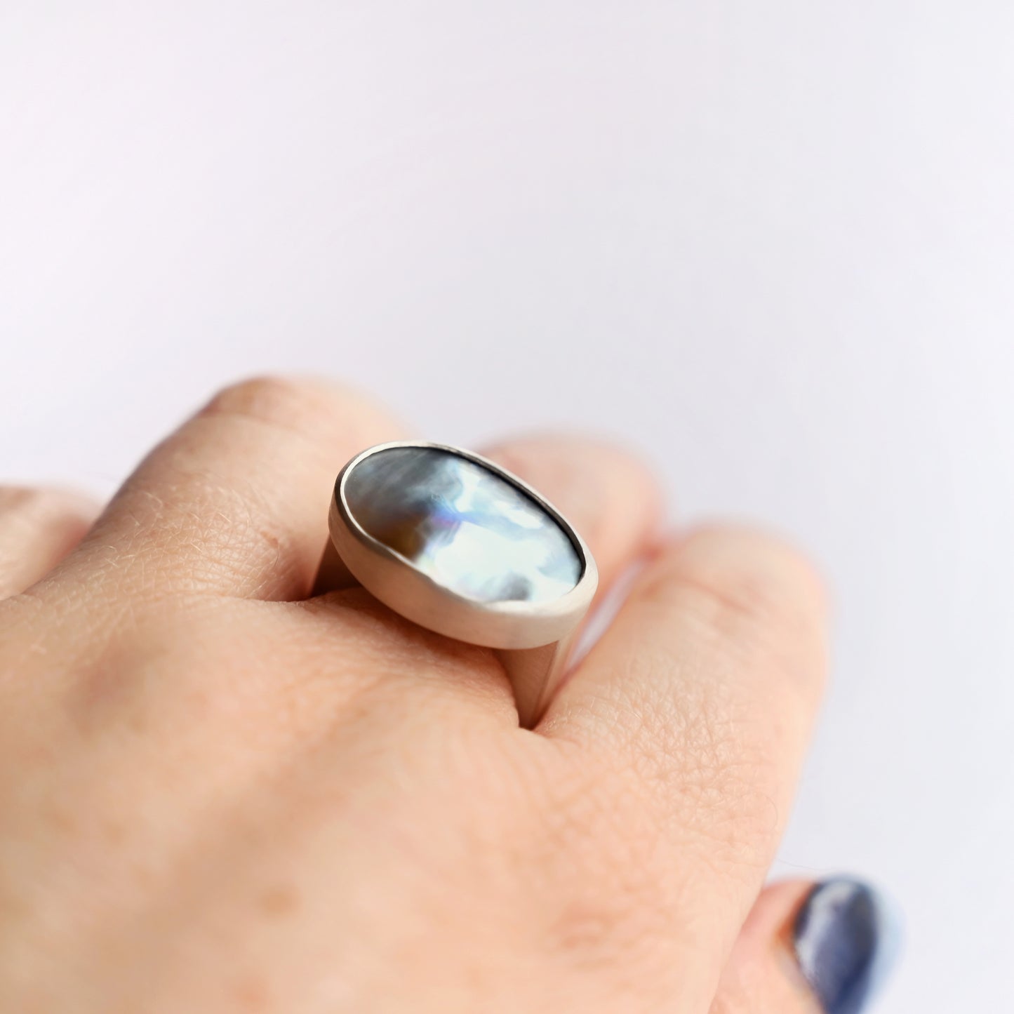 Top angled view of silver component ring with mabe pearl 1 on hand with white background
