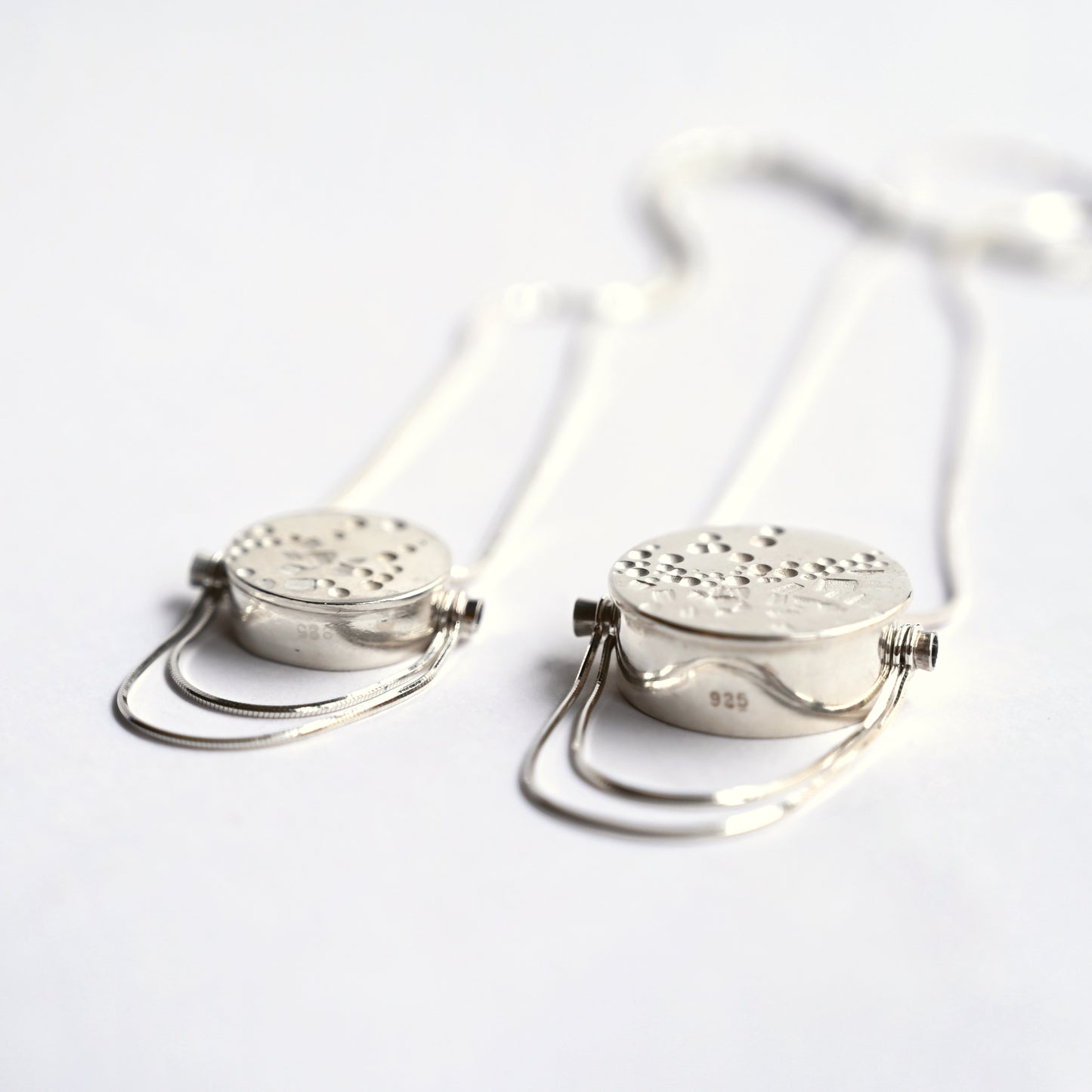 Silver box pendants with snake chain on white background, front angled view