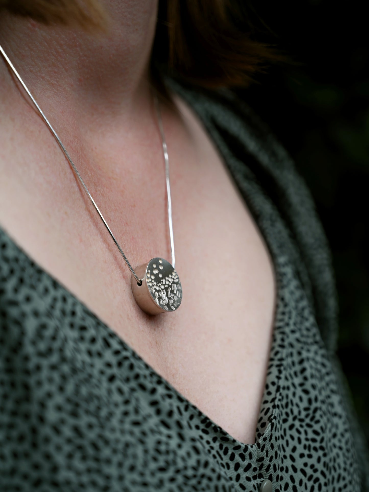 Contrast box pendant in silver with side view around model's neck with black background