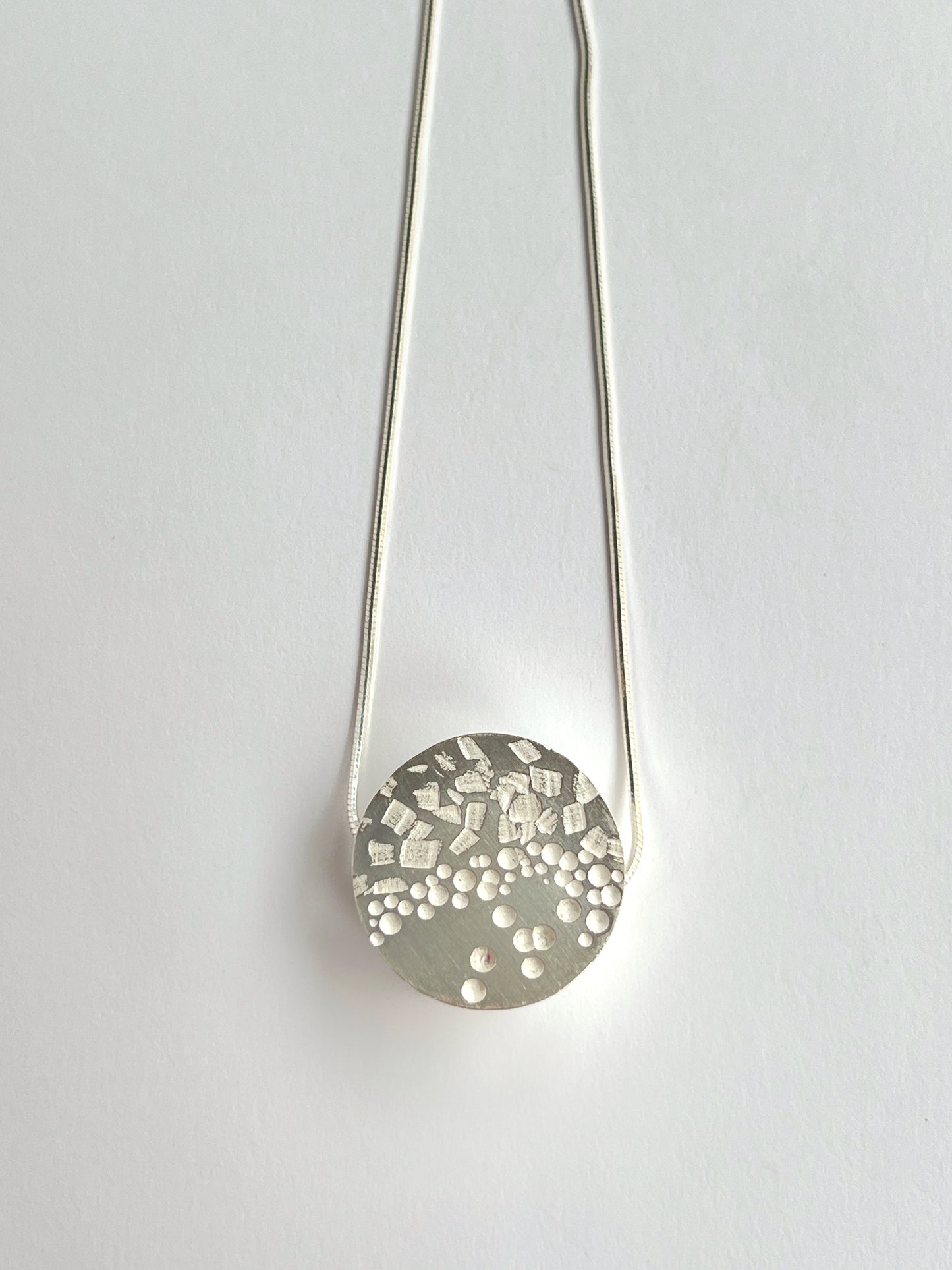 front angle of 1 circle small necklace laying flat on a white background