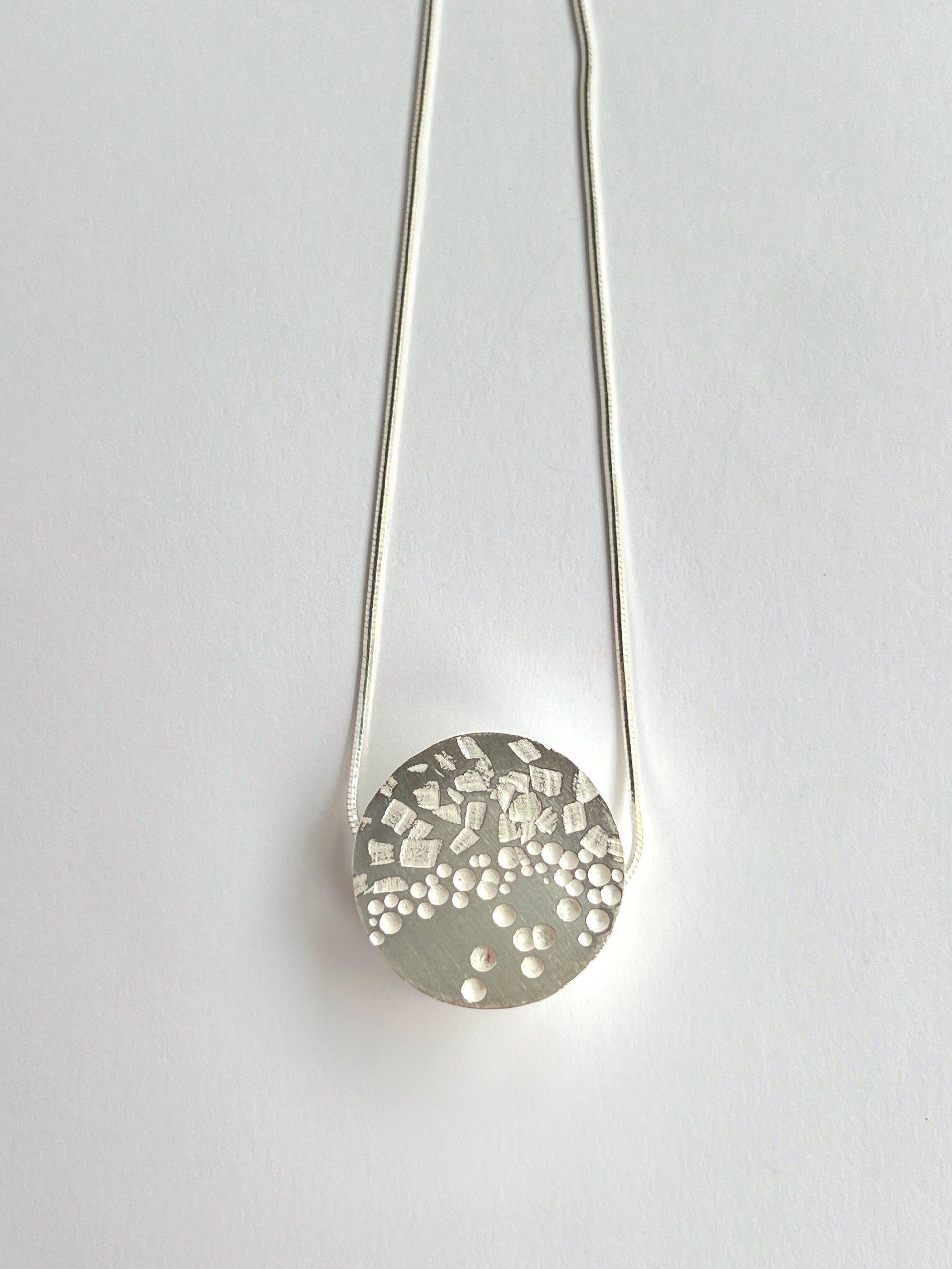 front angle of 1 circle small necklace laying flat on a white background
