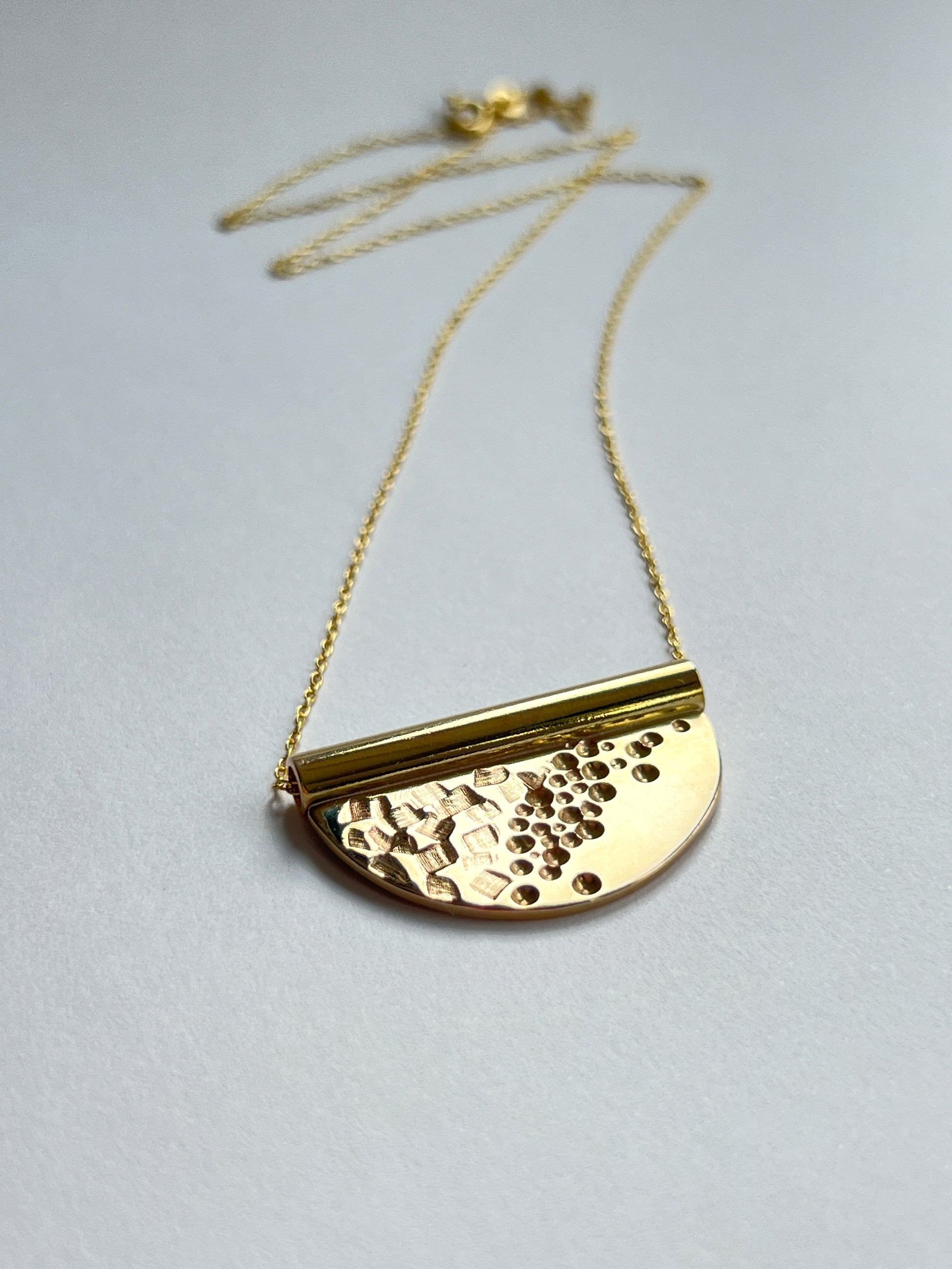 bronze tube necklace laying flat facing to the right with a white background