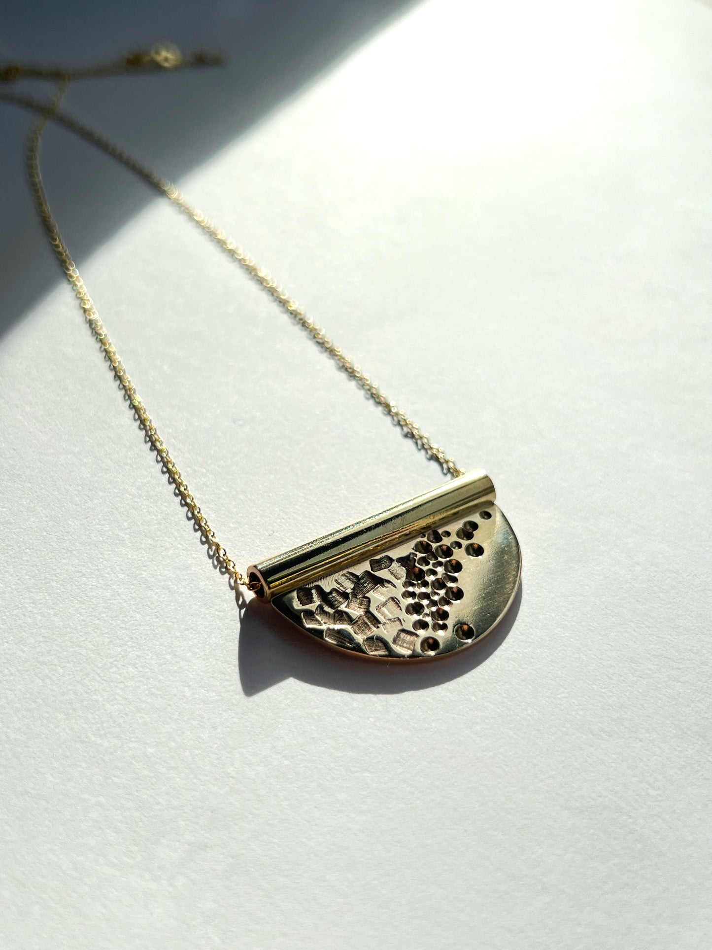 bronze tube necklace laying flat facing to the right on a 60 degree angle with a white background