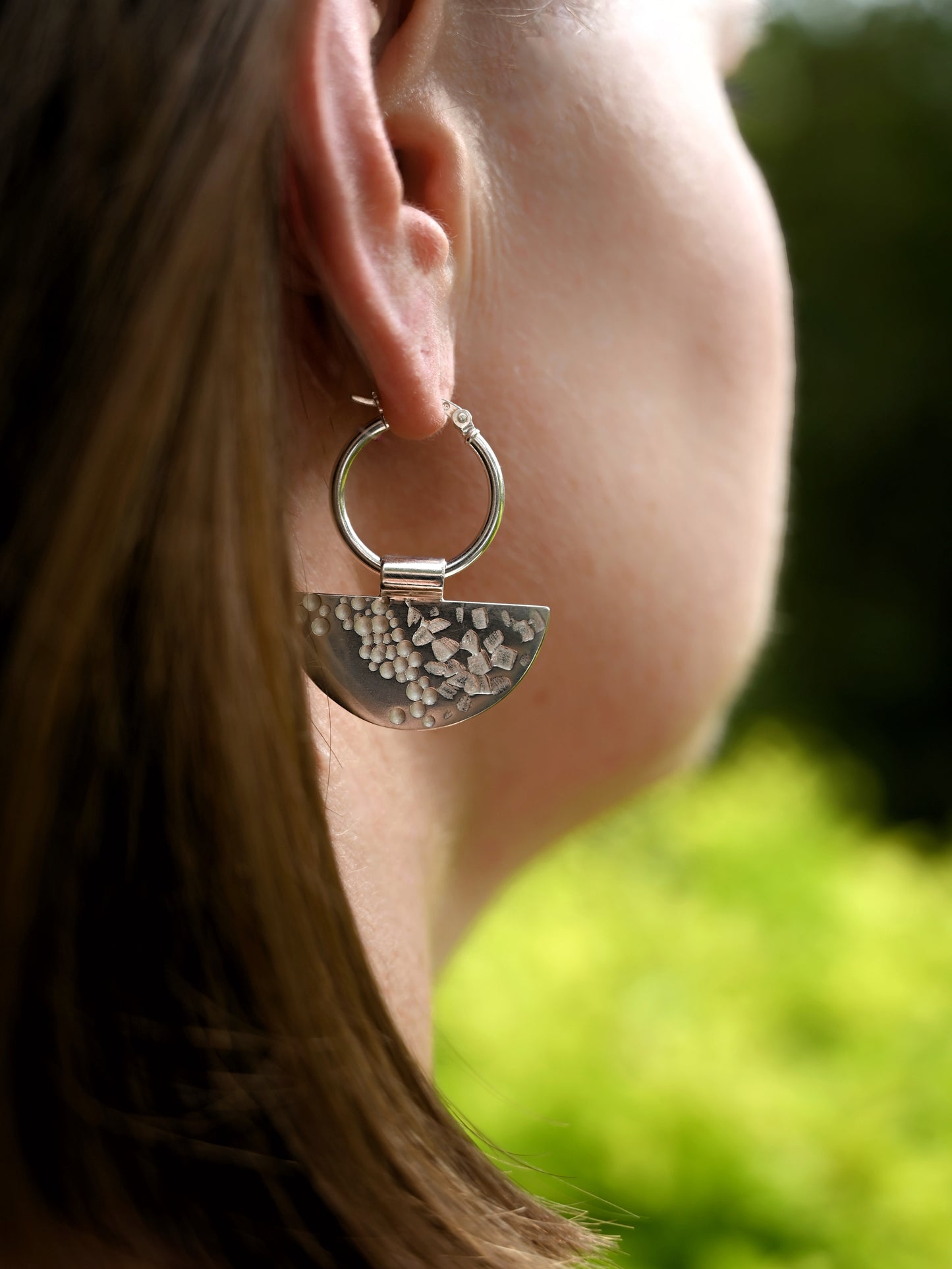 Contrast hoops on model from over shoulder with greenery in background