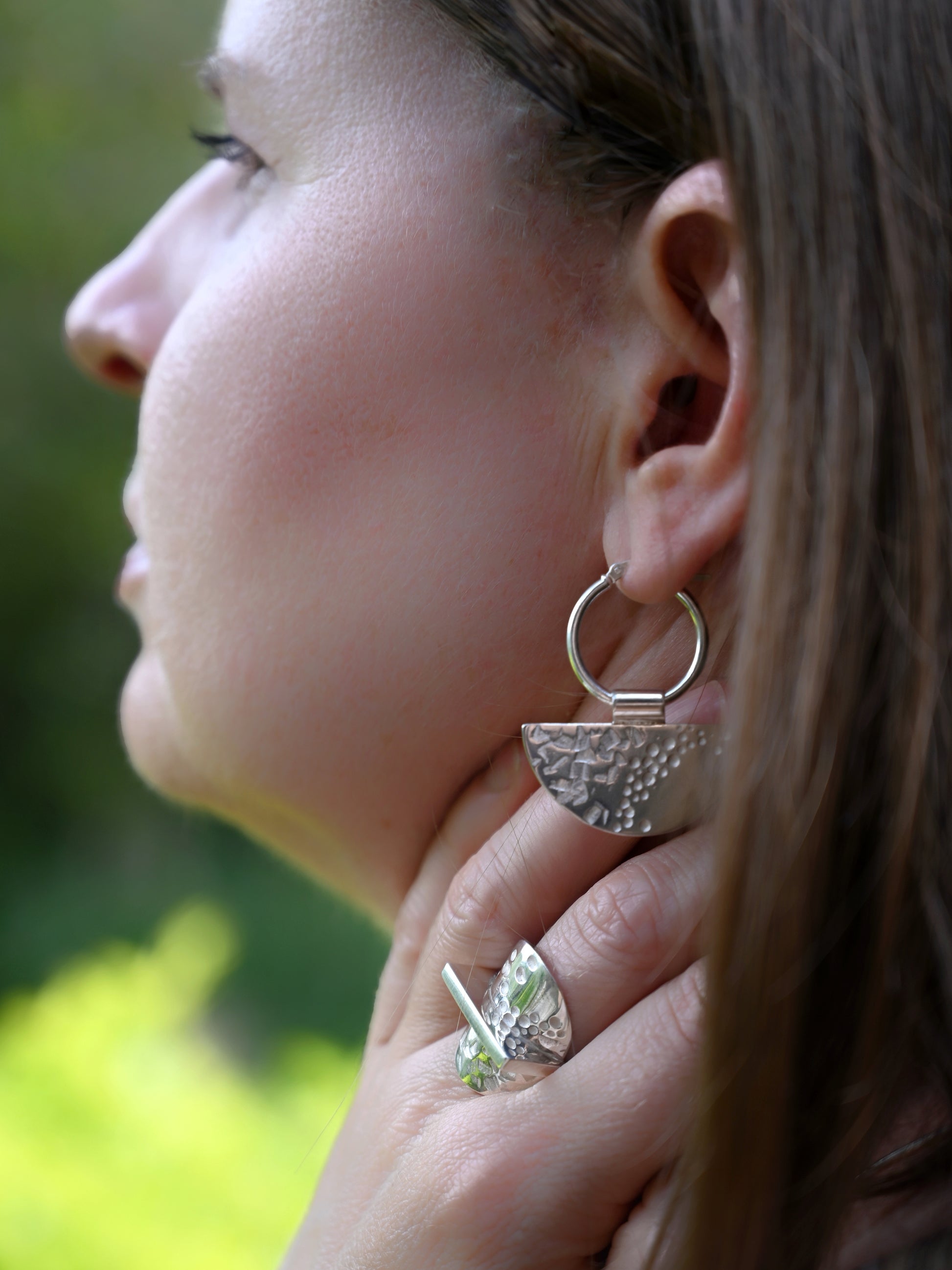 Side view of contrast hoops on model with greenery in background