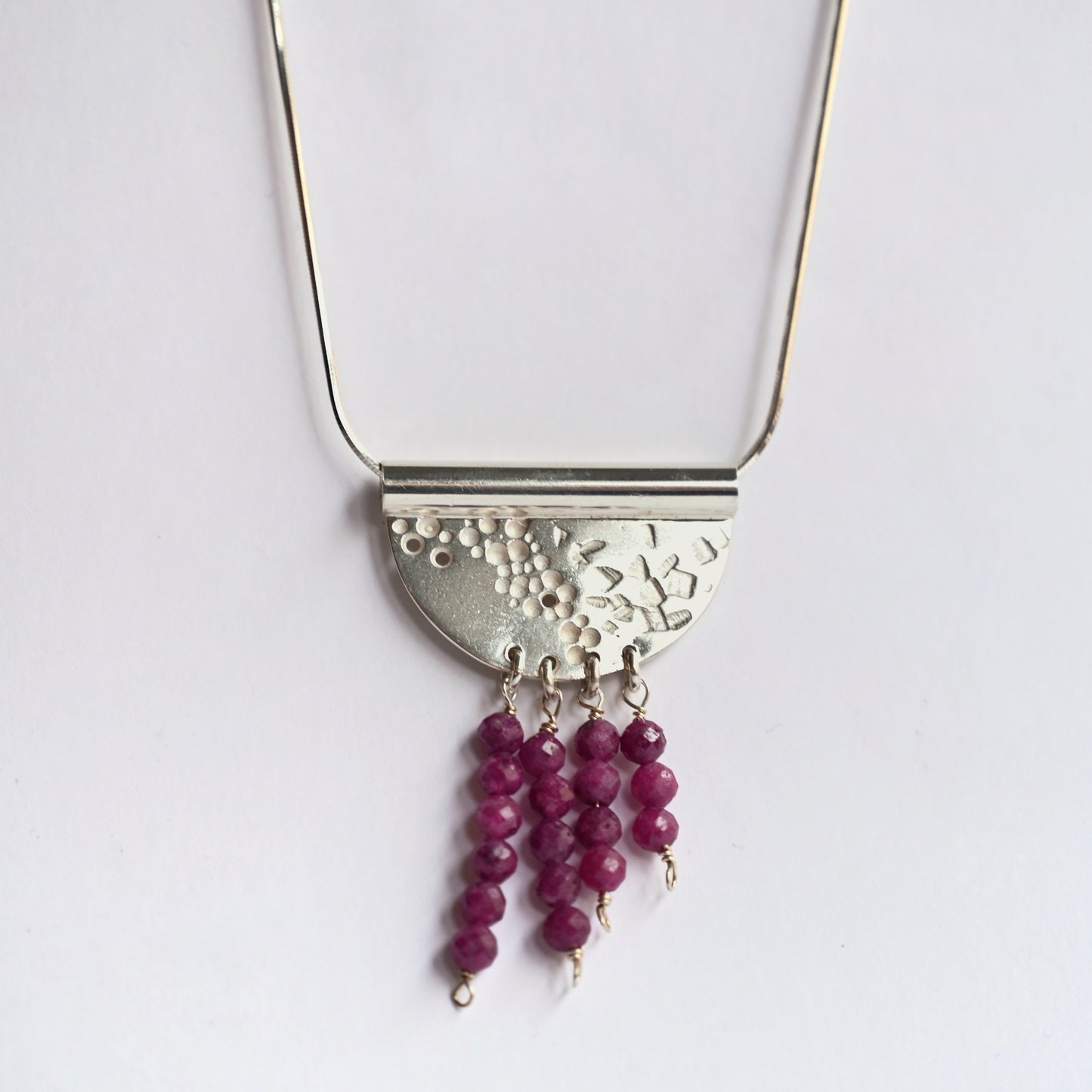 Contrast tube necklace with ruby from front on white background