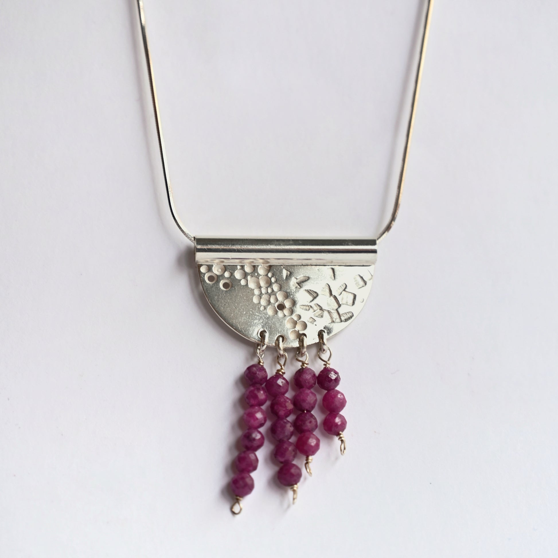 Contrast tube necklace with ruby from front on white background