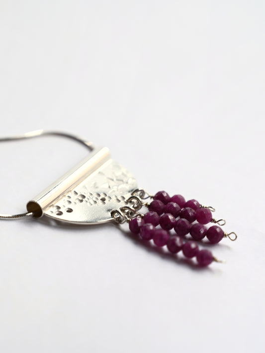Contrast tube necklace with ruby from side on white background
