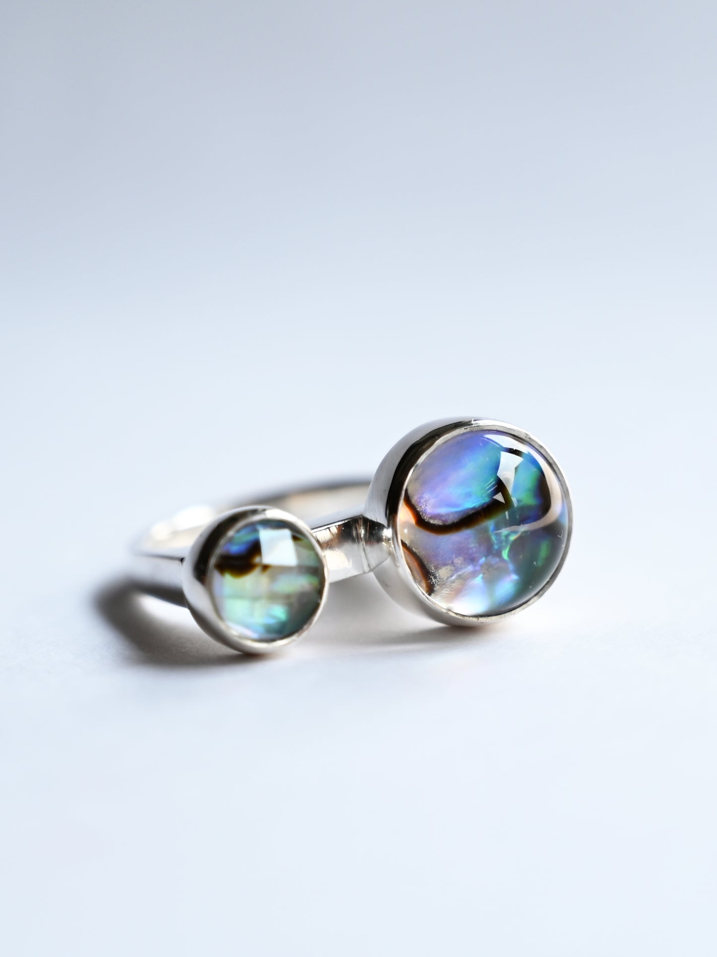 Component silver ring with cabochon & faceted Abalone gemstones on white background