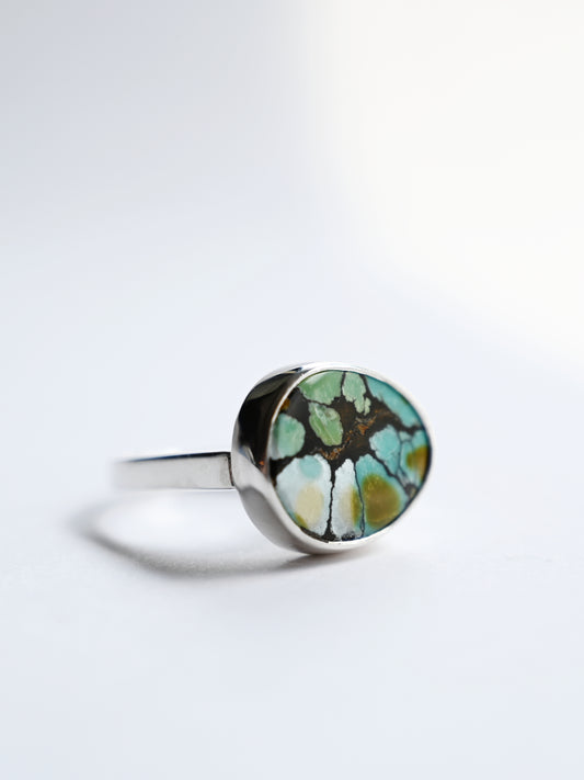 Sterling silver component ring with Could mountain Turquoise on side with white background.
