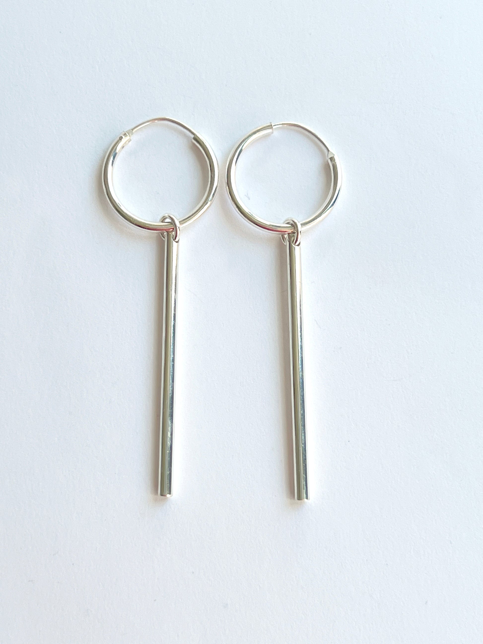 long tube dangle sterling silver hoops on a white background