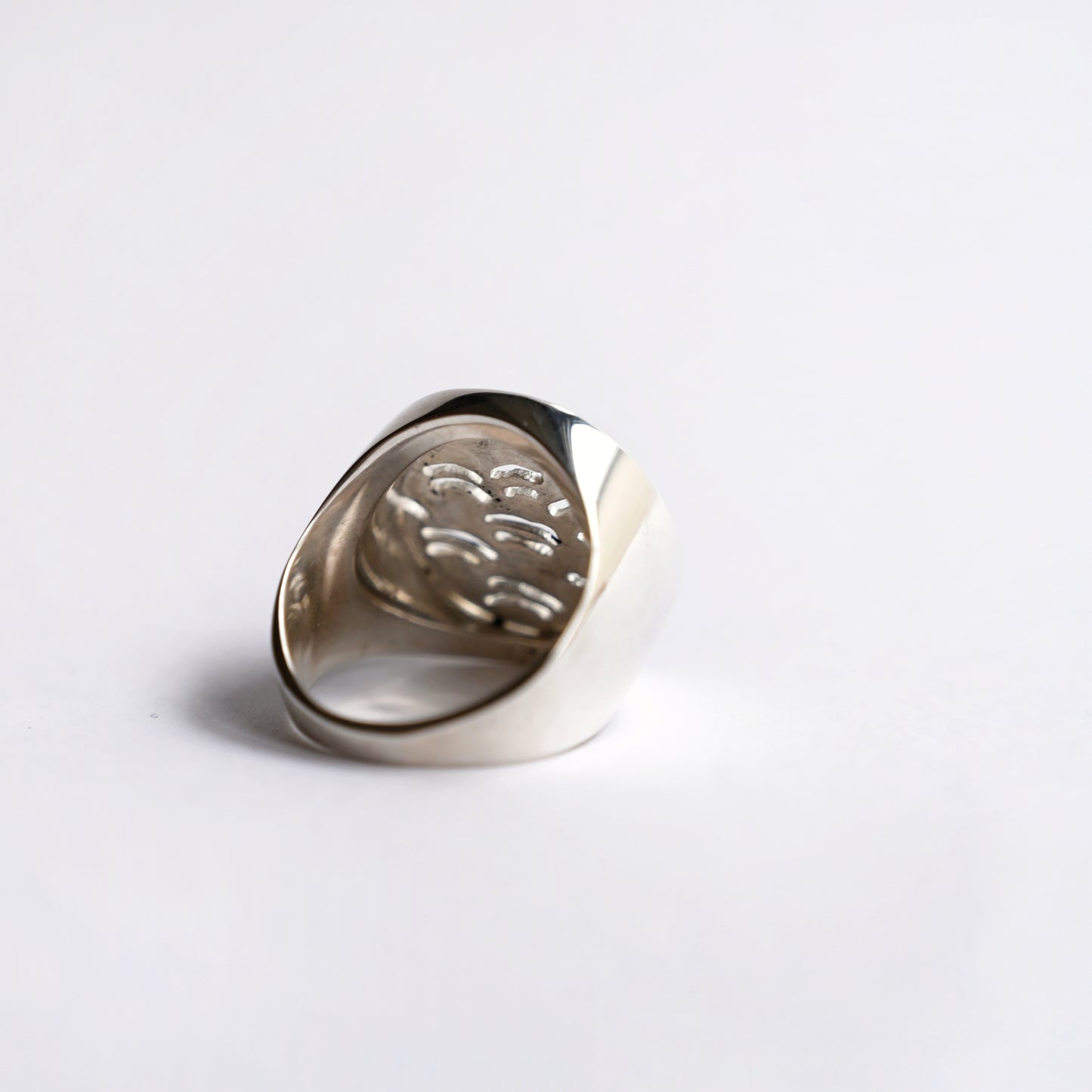 Node ring in silver with wave pattern cut out from back on white background