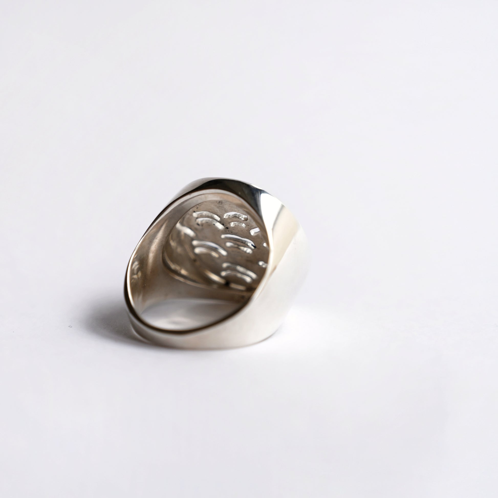Node ring in silver with wave pattern cut out from back on white background