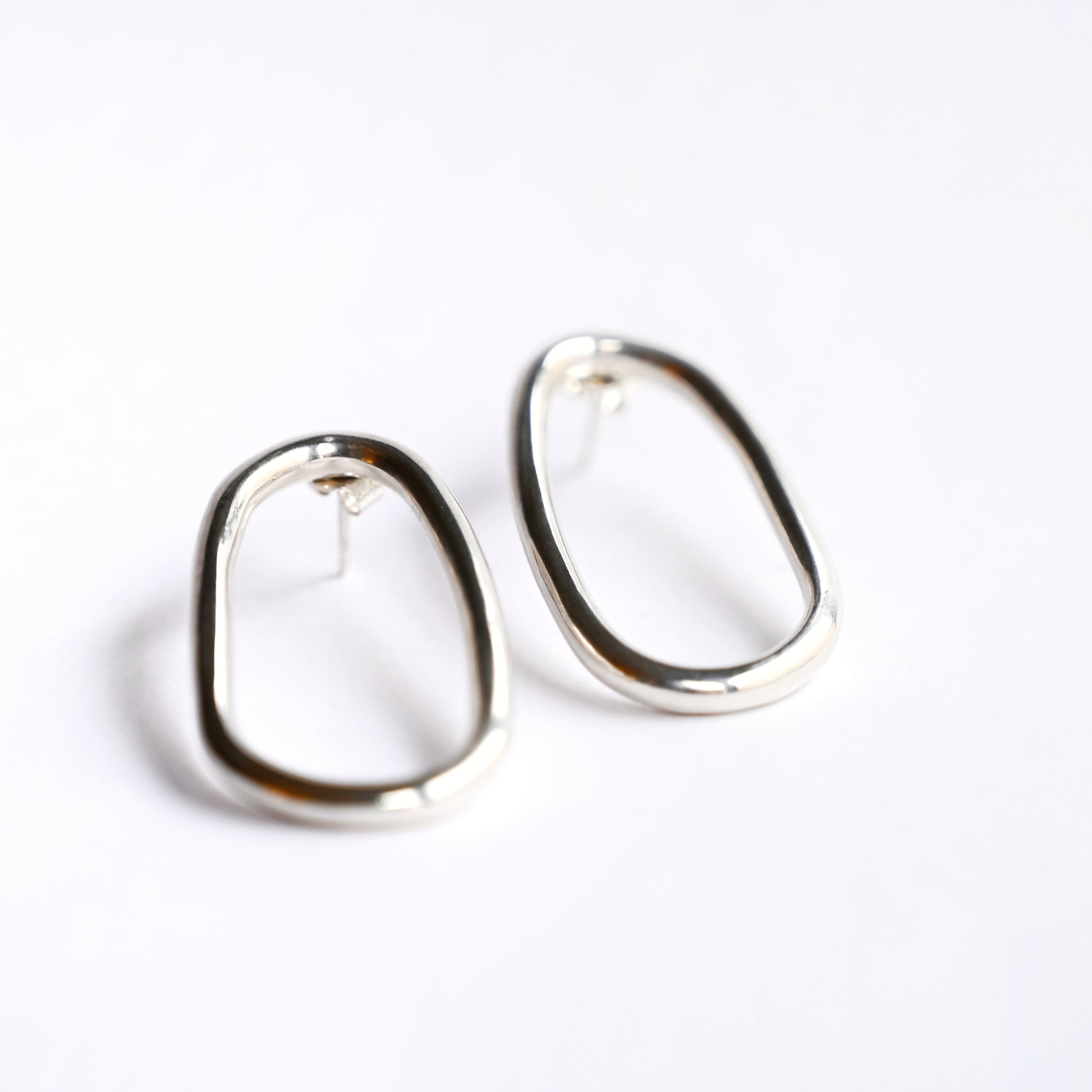 Large silver oval drop studs from front on white background