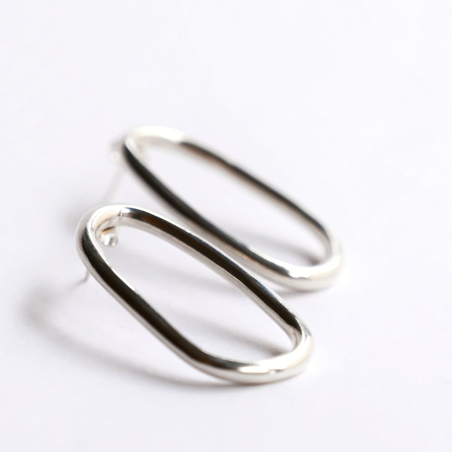 Large oval silver studs from side on white background