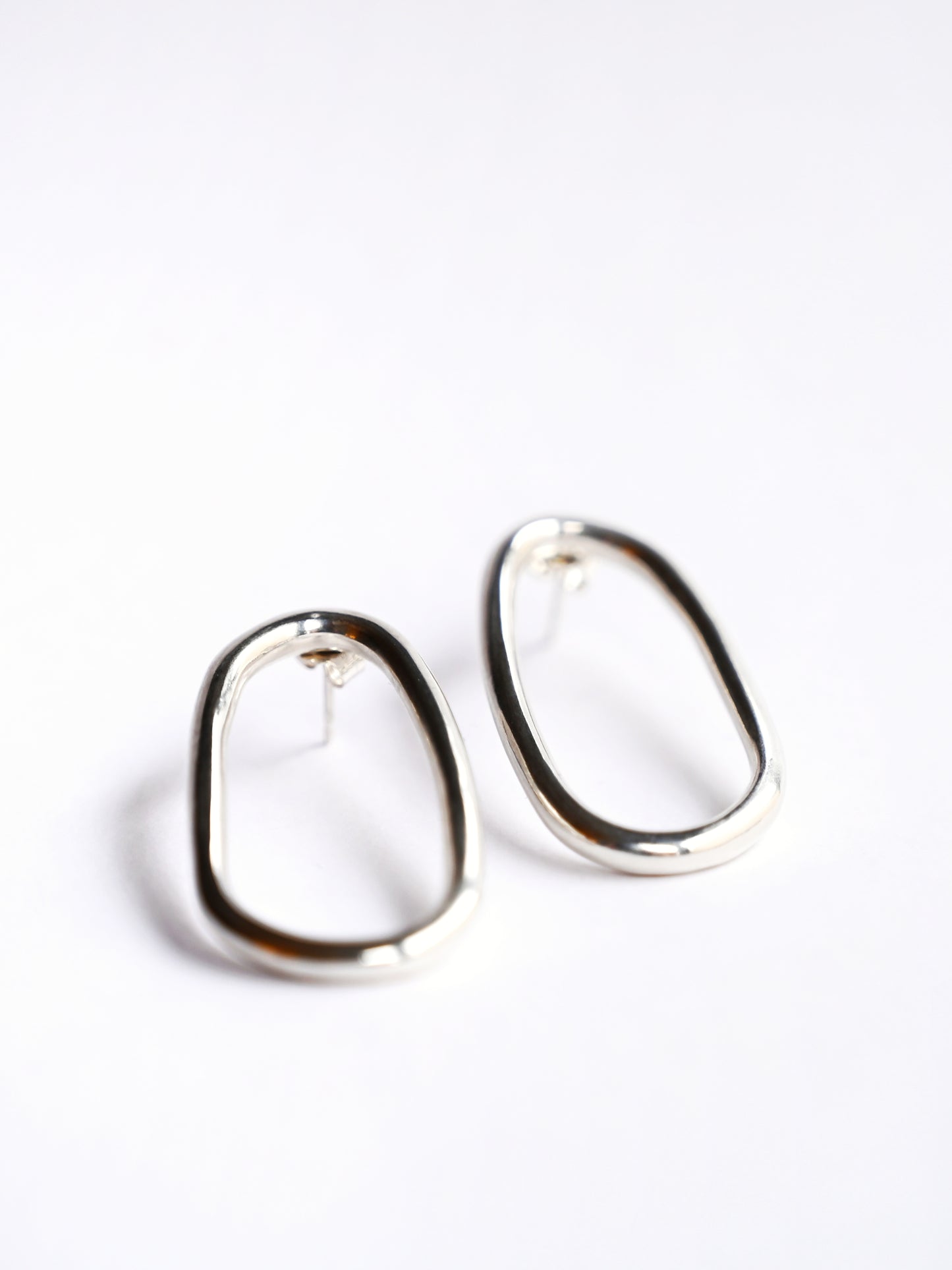 Small silver oval drop studs from front on white background