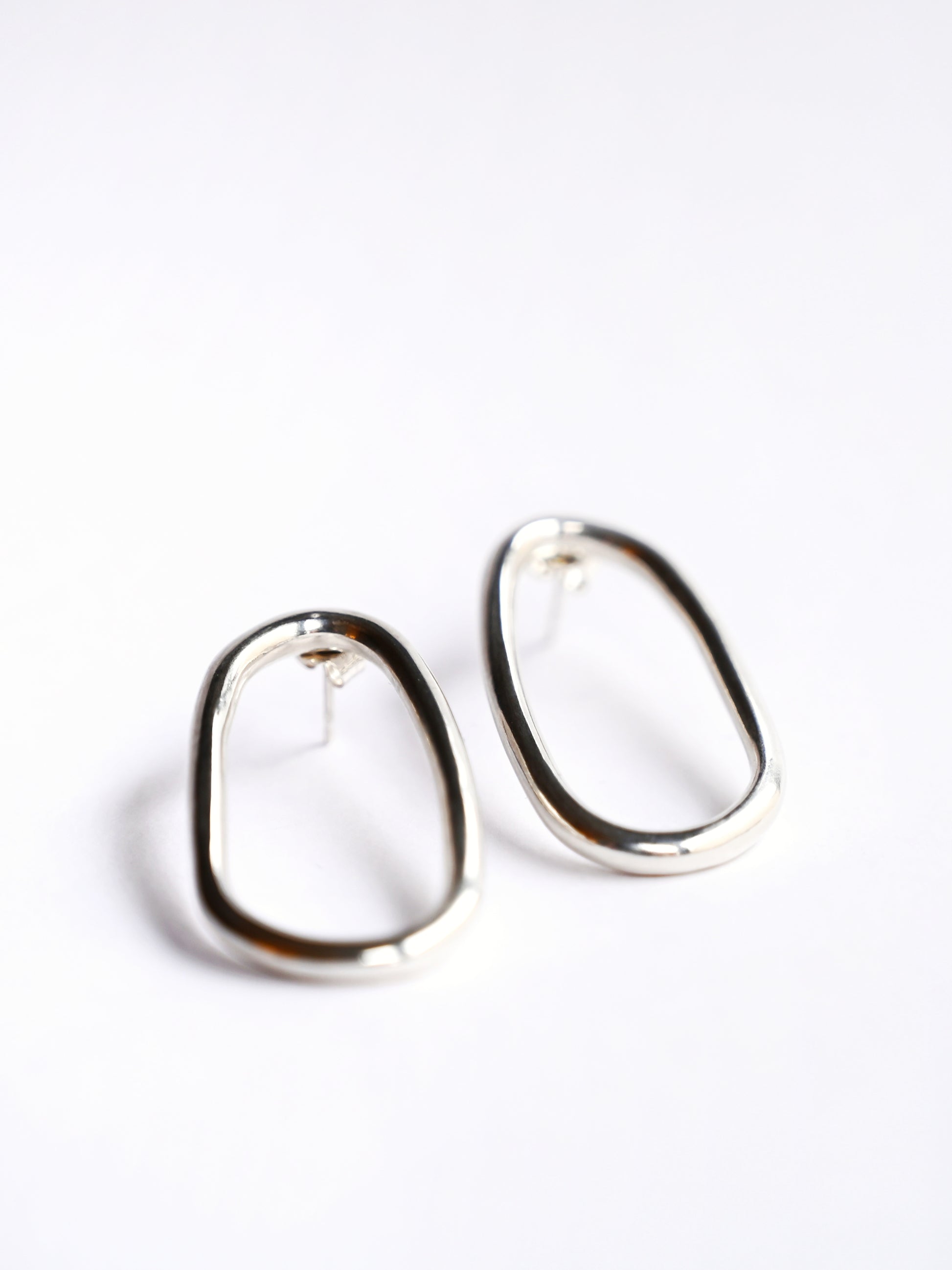 Small silver oval drop studs from front on white background