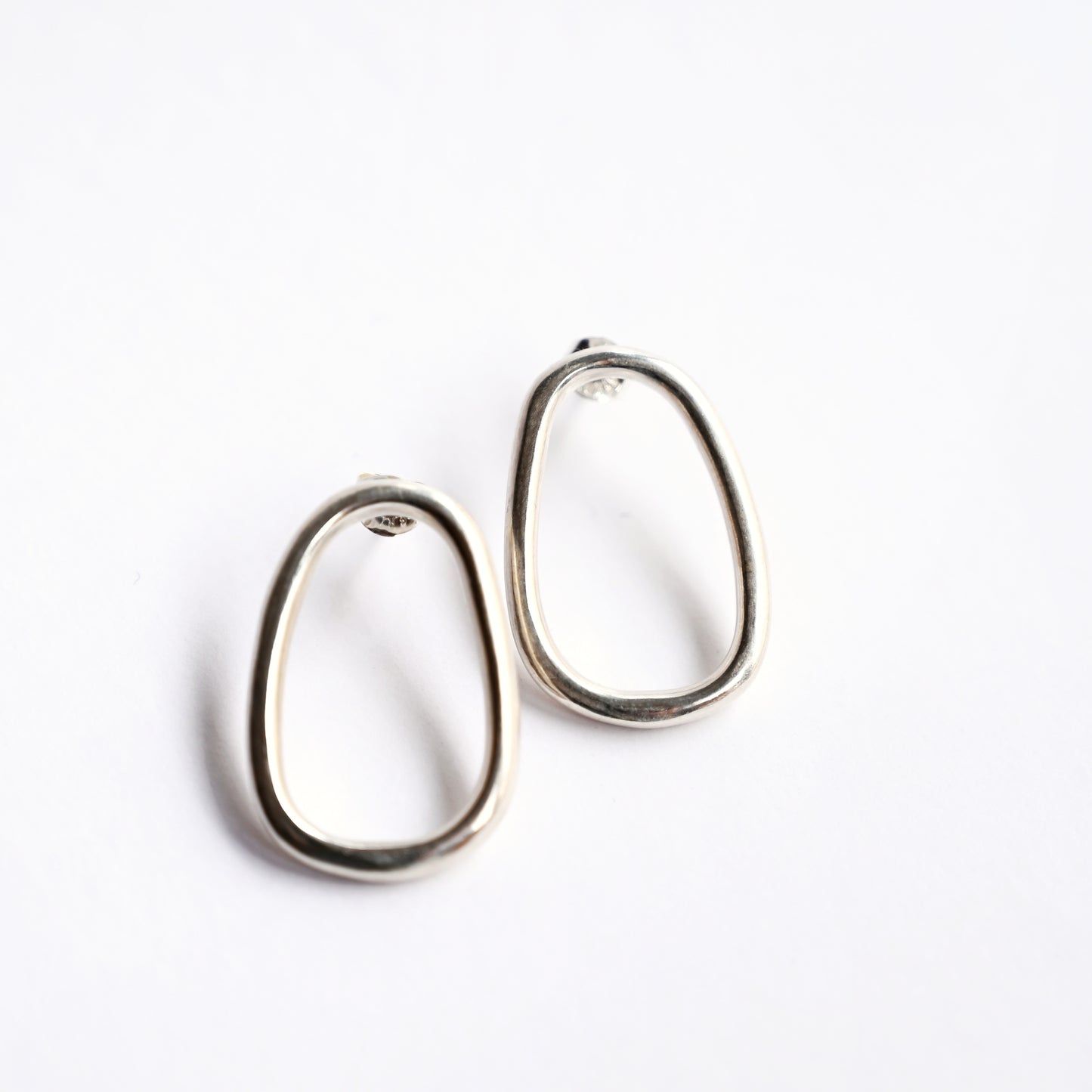 Small silver oval drop studs from top on white background