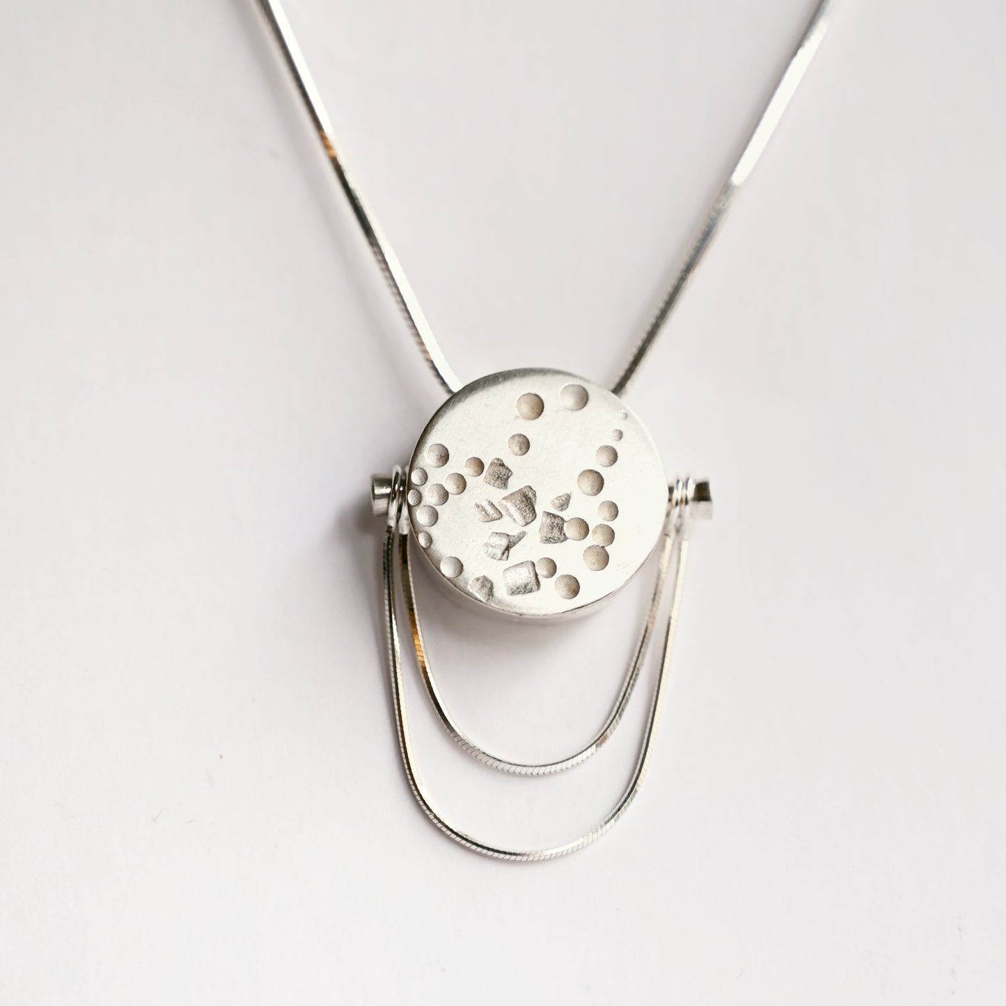Front view of small silver contrast box pendant with snake chains on white background