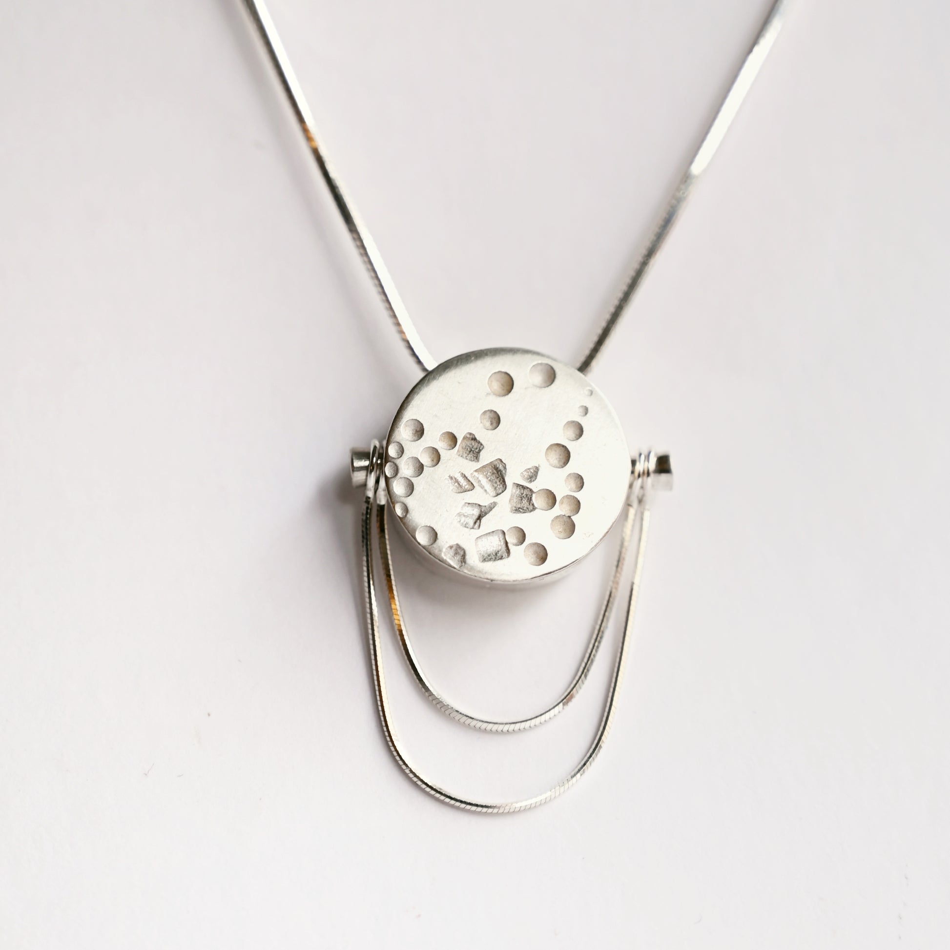 Front view of small silver contrast box pendant with snake chains on white background
